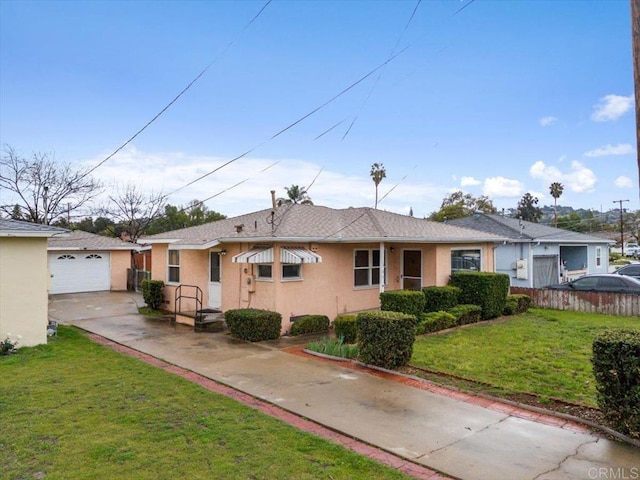 ranch-style home featuring fence, stucco siding, a front lawn, concrete driveway, and an outdoor structure