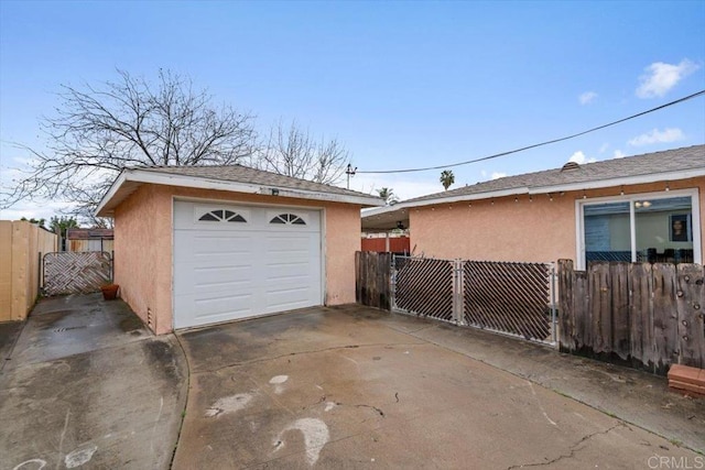 detached garage featuring concrete driveway and fence