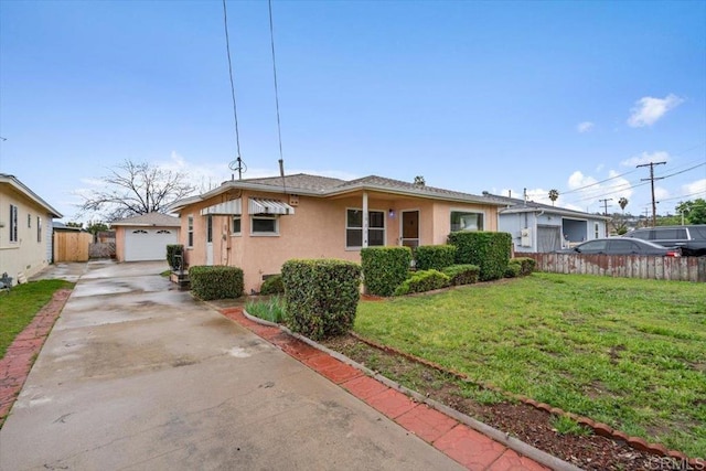 view of front of property featuring a front lawn, fence, concrete driveway, stucco siding, and an outbuilding