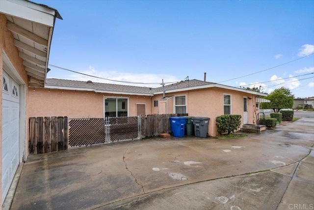 exterior space featuring stucco siding, roof with shingles, and fence