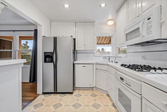 kitchen with backsplash, white cabinets, white appliances, and tile counters