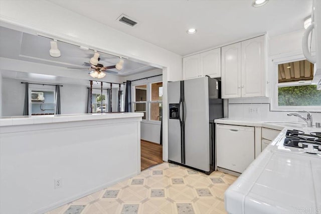 kitchen with visible vents, a sink, stainless steel fridge with ice dispenser, white dishwasher, and tile counters