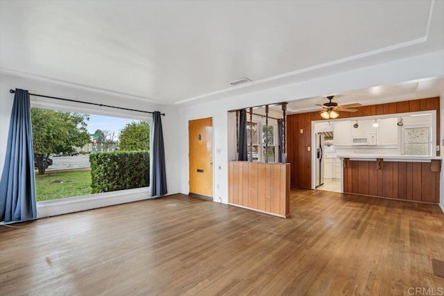 unfurnished living room with visible vents, wood finished floors, and a ceiling fan