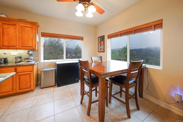 dining space with baseboards, light tile patterned flooring, and a ceiling fan