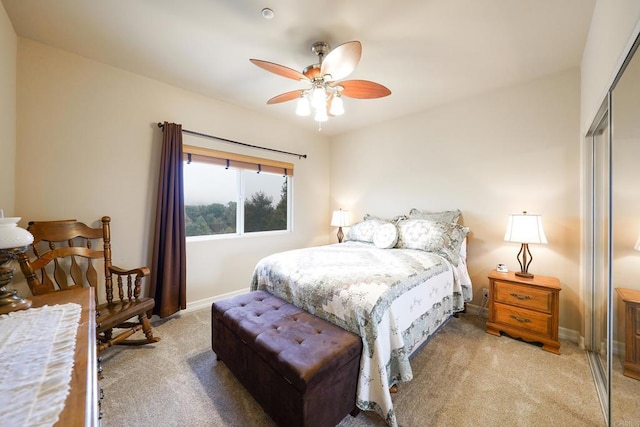 bedroom featuring a closet, light carpet, baseboards, and a ceiling fan