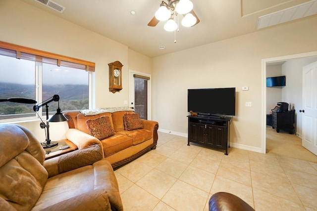 living room with light tile patterned floors, visible vents, baseboards, and a ceiling fan