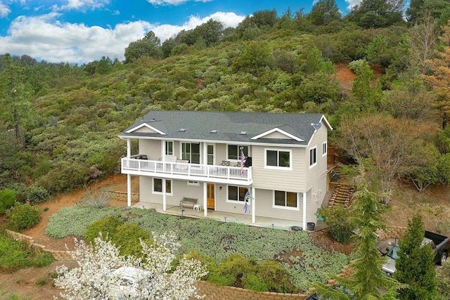 back of house with a patio area, stairway, and a forest view