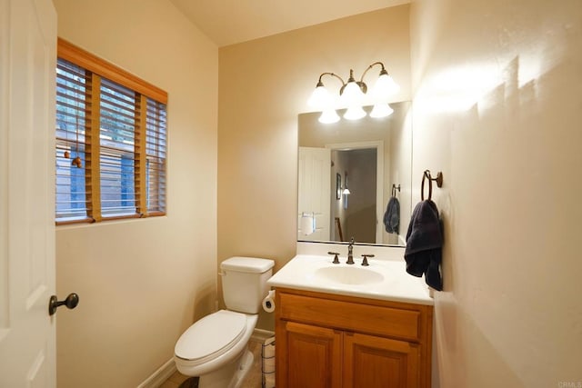 half bath featuring toilet, vanity, and baseboards