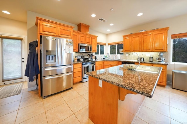 kitchen with stainless steel appliances, backsplash, visible vents, and a center island