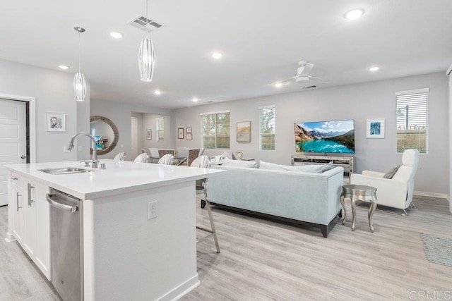 kitchen featuring a sink, stainless steel dishwasher, a healthy amount of sunlight, and open floor plan