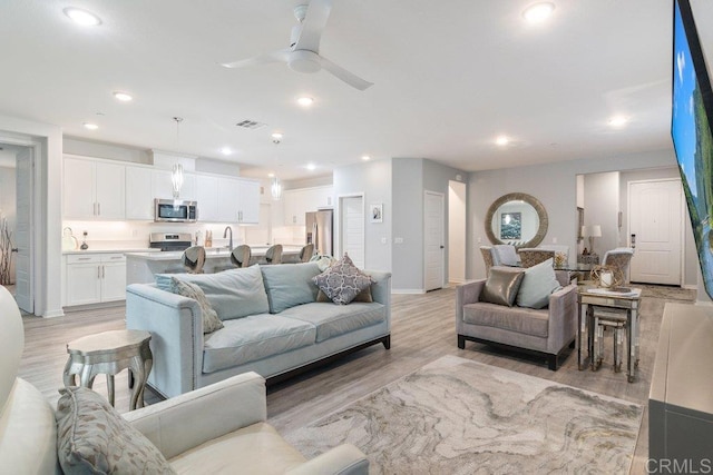 living area with visible vents, baseboards, ceiling fan, recessed lighting, and light wood-style floors