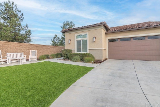 view of front of property with a front yard, fence, an attached garage, stucco siding, and concrete driveway