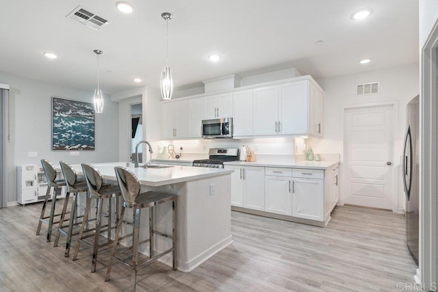 kitchen featuring visible vents, stainless steel appliances, light countertops, and a sink