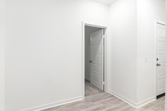 corridor with baseboards and light wood-type flooring