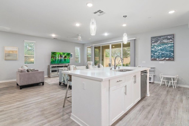 kitchen featuring light wood finished floors, open floor plan, dishwasher, an island with sink, and a sink