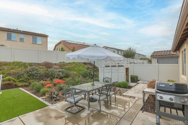 view of patio / terrace with an outbuilding, outdoor dining space, a fenced backyard, and area for grilling