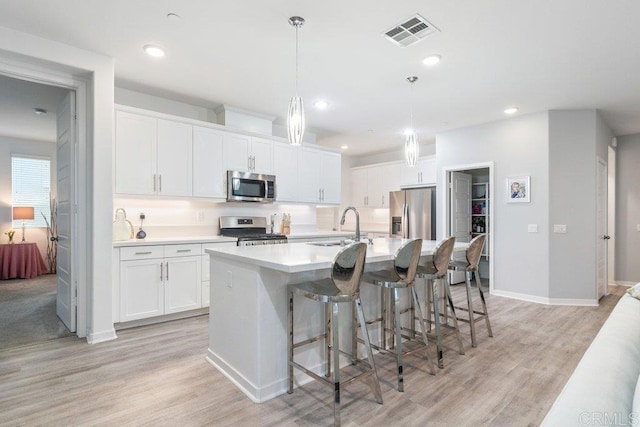 kitchen with visible vents, light countertops, appliances with stainless steel finishes, white cabinets, and a sink