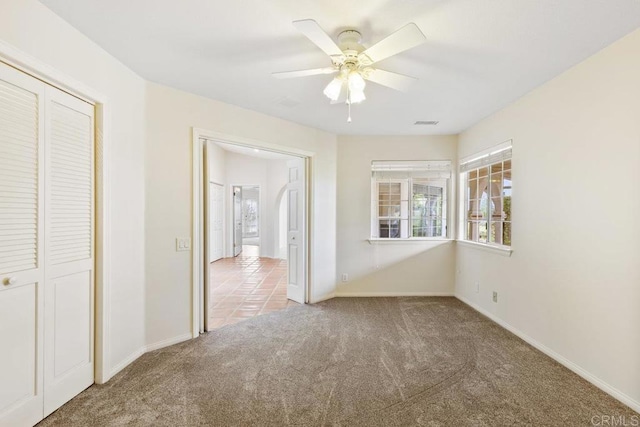 unfurnished bedroom featuring baseboards, visible vents, carpet floors, ceiling fan, and a closet