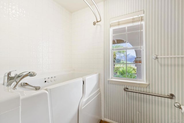 bathroom featuring tile walls and a tub to relax in