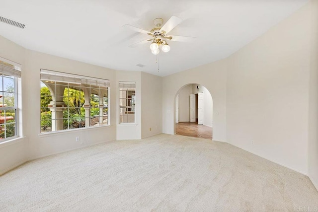 unfurnished room featuring a ceiling fan, visible vents, arched walkways, and carpet floors