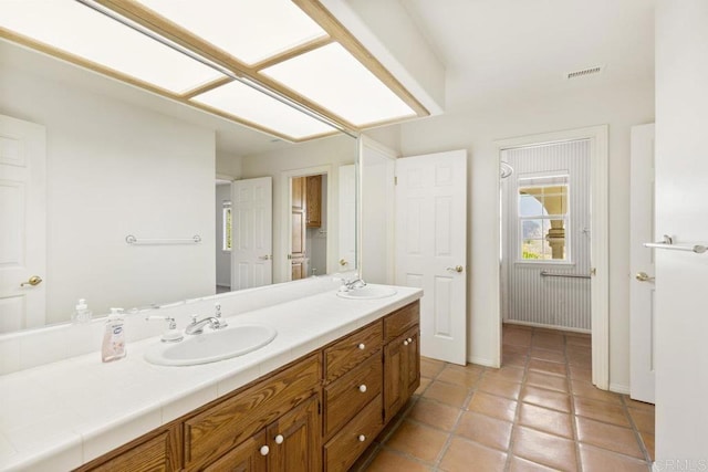 bathroom with tile patterned flooring, double vanity, visible vents, and a sink