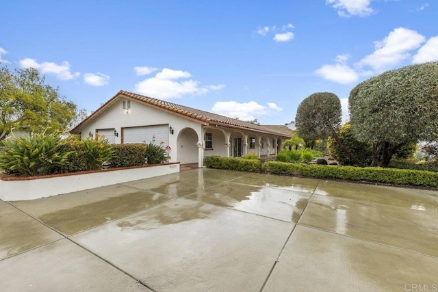 mediterranean / spanish home featuring a tile roof, stucco siding, concrete driveway, and a garage