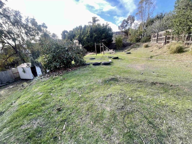 view of yard featuring an outdoor structure, a shed, and fence