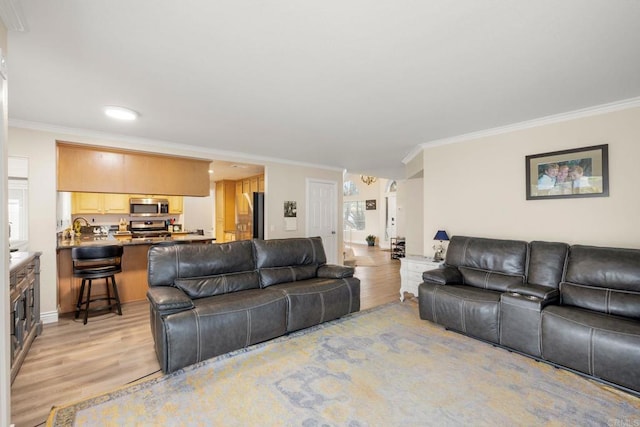 living area featuring light wood-style flooring and ornamental molding