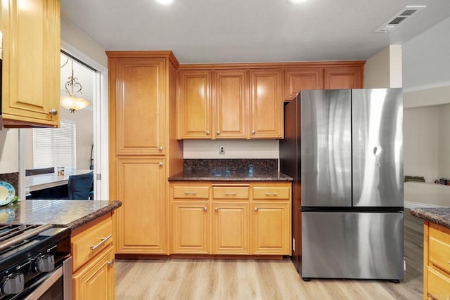 kitchen featuring dark stone counters, light wood-style flooring, visible vents, and appliances with stainless steel finishes