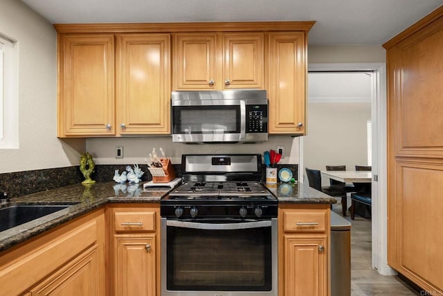 29600 Nightcrest Cir, Temecula, CA 92591 - kitchen featuring dark stone countertops, wood finished floors, a sink, brown cabinetry, and appliances with stainless steel finishes