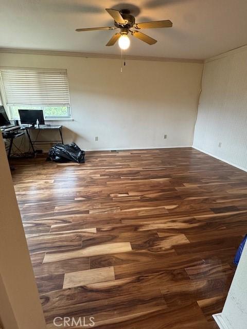 empty room with wood finished floors, a ceiling fan, and ornamental molding