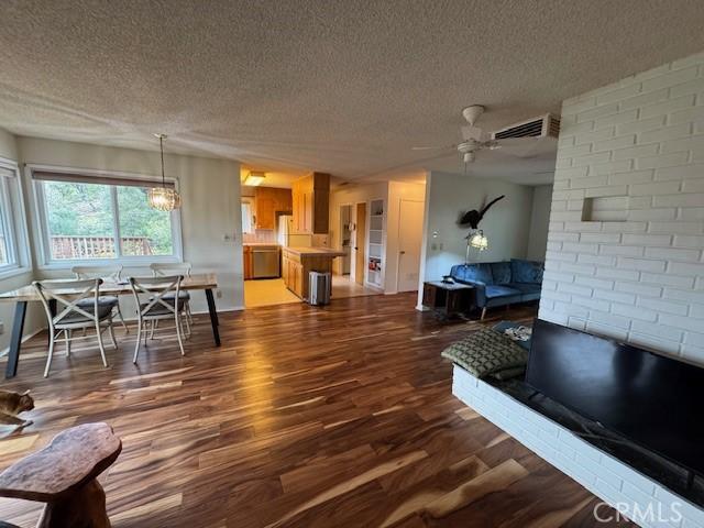 living area featuring dark wood finished floors, a ceiling fan, visible vents, and a textured ceiling