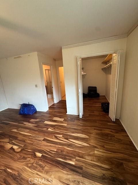 unfurnished bedroom with a closet, ornamental molding, and wood finished floors