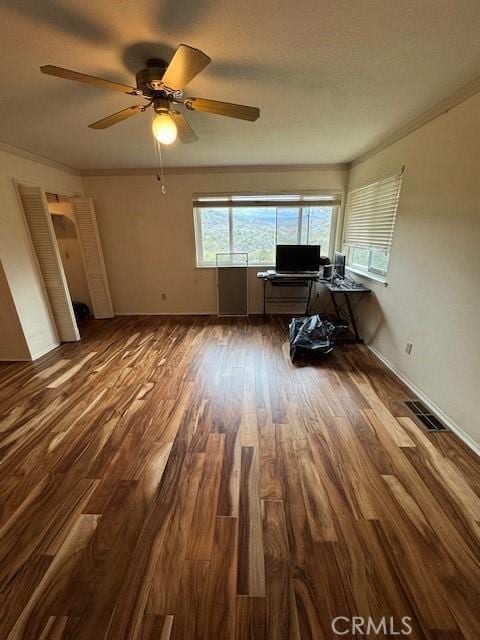 unfurnished office with dark wood finished floors, baseboards, visible vents, and ornamental molding