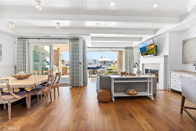 dining area featuring beam ceiling, wood-type flooring, and a wealth of natural light