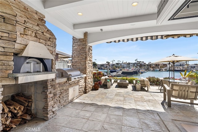 view of patio with grilling area, exterior kitchen, and a water view