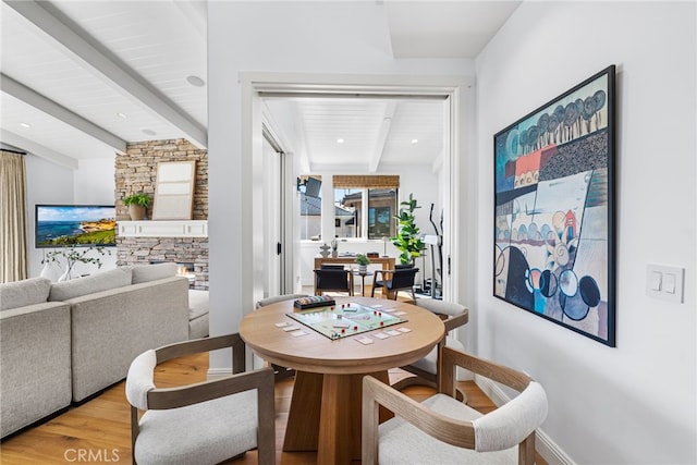 dining area featuring beam ceiling, recessed lighting, a fireplace, and wood finished floors