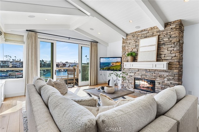 living room with a stone fireplace, vaulted ceiling with beams, and wood finished floors