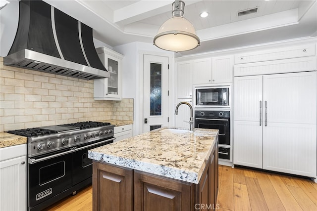 kitchen with visible vents, light wood-type flooring, black appliances, a sink, and wall chimney range hood