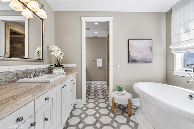 bathroom with vanity, tile patterned floors, baseboards, and a freestanding bath