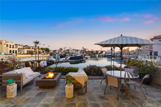 view of patio / terrace featuring outdoor dining area, an outdoor living space with a fire pit, a dock, and a water view