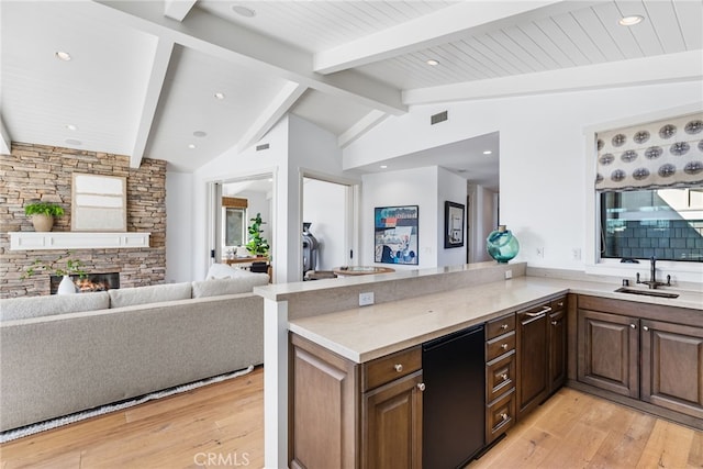 kitchen with visible vents, vaulted ceiling with beams, open floor plan, a fireplace, and a sink