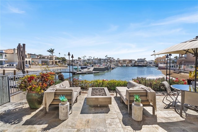 view of patio / terrace featuring a dock, an outdoor living space with a fire pit, and a water view