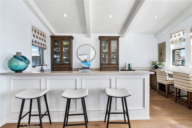 bar with light wood-style flooring, vaulted ceiling with beams, and recessed lighting