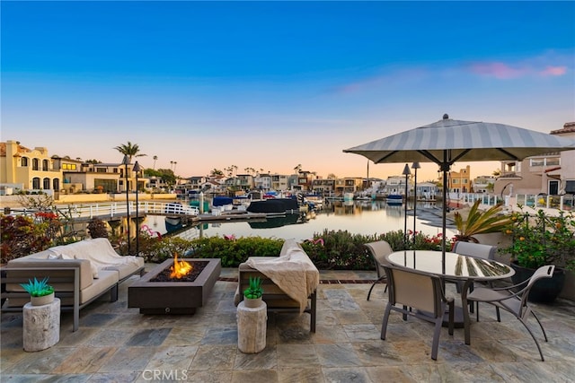 patio terrace at dusk featuring an outdoor living space with a fire pit and outdoor dining area