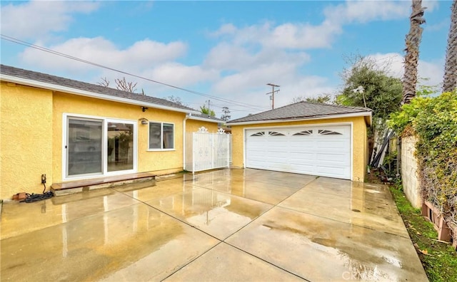 exterior space with an outbuilding, stucco siding, a detached garage, and fence