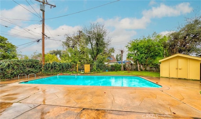 view of swimming pool with an outbuilding, a fenced in pool, a patio, and fence