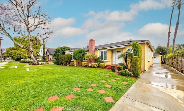 view of front of home with a front yard, stucco siding, a chimney, a garage, and an outdoor structure