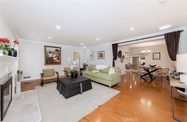 living room with crown molding, wood finished floors, a chandelier, and a premium fireplace