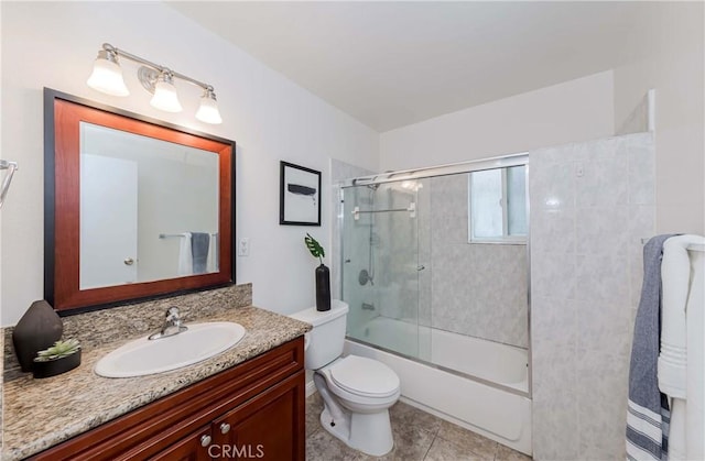 bathroom with tile patterned flooring, toilet, vanity, and bath / shower combo with glass door